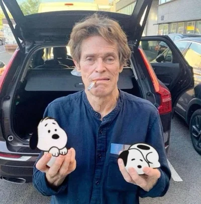 Willem Defoe holding two snoopies 